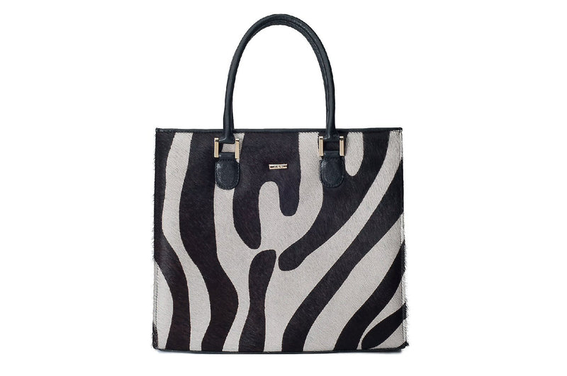Linda front view Adele Exclusive Luxury Design Black bovine leather side, back and bottom panel, with white and black zebra printed hair on hide on the front panel. Contains an inside zipper with a back-zip pocket. The bag interior consists of high-quality black cotton suede lining. Includes a top zip closure with gold plated hardware, and a detachable shoulder strap with an adjustable buckle. Bag feet studs are located on the bottom panel.
