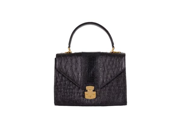 Front view black ostrich and shin constructed top flap handbag with an Italian lock closure. Contains inside back zipper pocket and a front inside zip pocket. High quality black leather interior. Includes a top handle with 24 carat gold plated fittings, detachable shoulder strap, adjustable buckle. Bottom bag feet studs.