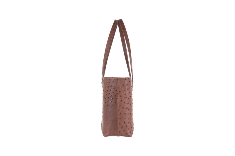 Side view ostrich leather shopper style bag with two shoulder straps and decorative hardware. Magnetic top closure. Suede leather lining and multiple Inside pockets. Inside key leather strap.