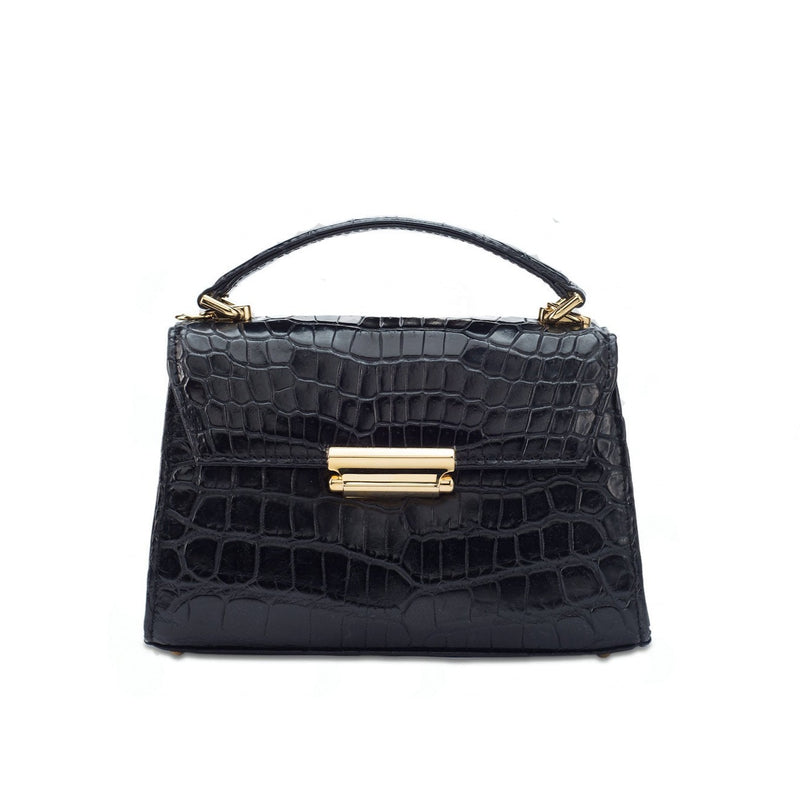 Front front view black crocodile leather constructed top flap handbag with press lock. Detachable adjustable shoulder strap. The bag contains an inside zipper with a back zip pocket. High quality black leather lining. Attached is a top handle with 24 carat gold plated fittings. The bottom panel features bag feet studs.