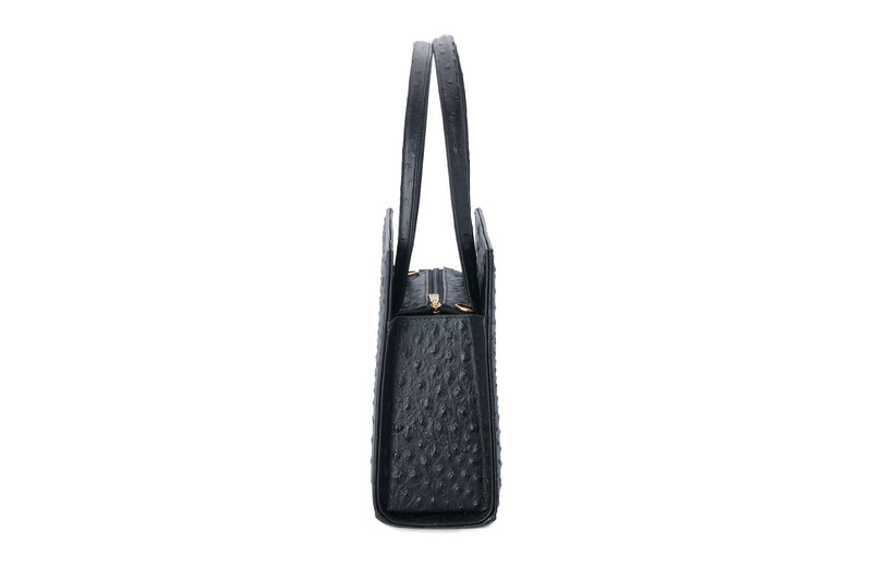 Side view black ostrich leather bag with a raised front and back panel and attached handles. Top zip closure with an inside zipper pocket and two open pockets. Interior consists of high quality black cotton lining. Comes with a detachable shoulder strap with an adjustable buckle.