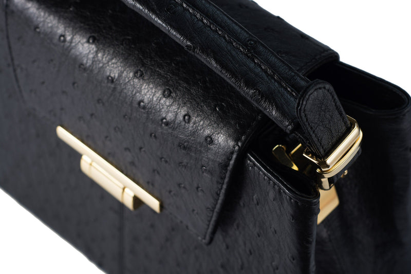 Top side front view ostrich leather constructed top flap handbag with an Italian lift lock closure. Inside zipper pocket, leather suede interior. Top handle 24 carat gold plated hardware,detachable shoulder strap with adjustable buckle. Bottom feet studs.