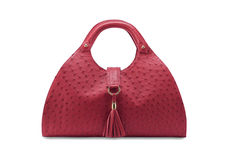 Front view Kimberley red ostrich Leather bag with fold over magnetic strap with D-ring & tassel decoration. Attached round shaped handles decorated with a studs. 