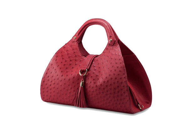 Front side view Kimberley red ostrich Leather bag with fold over magnetic strap with D-ring & tassel decoration. Attached round shaped handles decorated with a studs. 