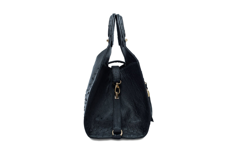 Side view Kimberley black ostrich Leather bag with fold over strap. Hidden magnet with D-ring & tassel decoration for closure. Attached round shaped handles decorated with a studs. Top snap hook closure internal zip pocket with two internal patch pockets. Black high quality suede leather lining, bag feet.